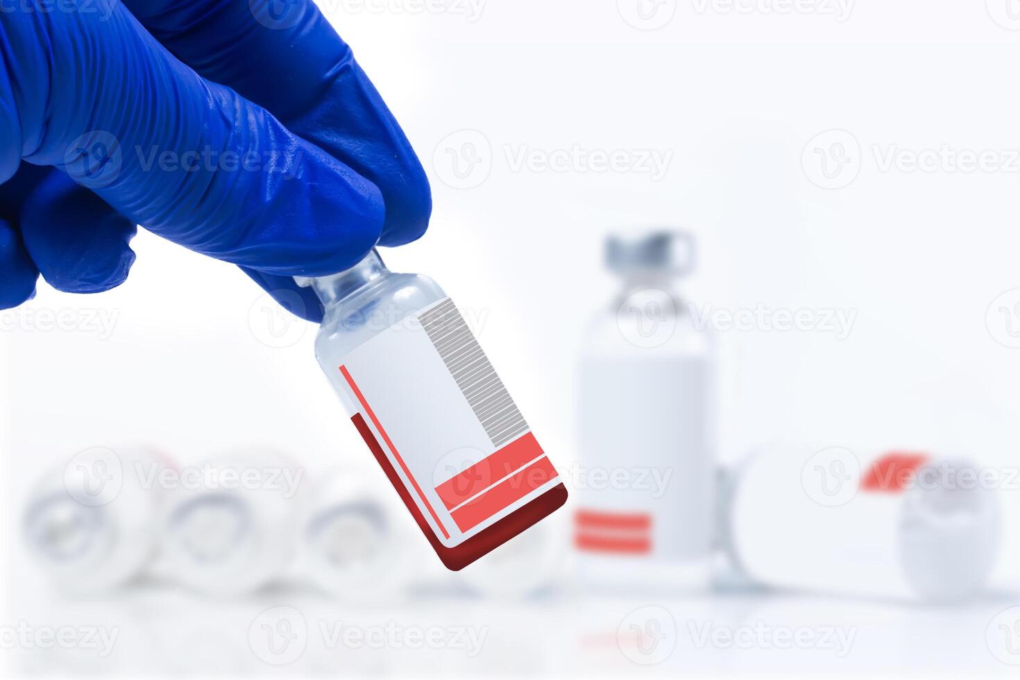 Hand in blue glove holding blood sample vial in front of blurred vaccine vials on white background. photo