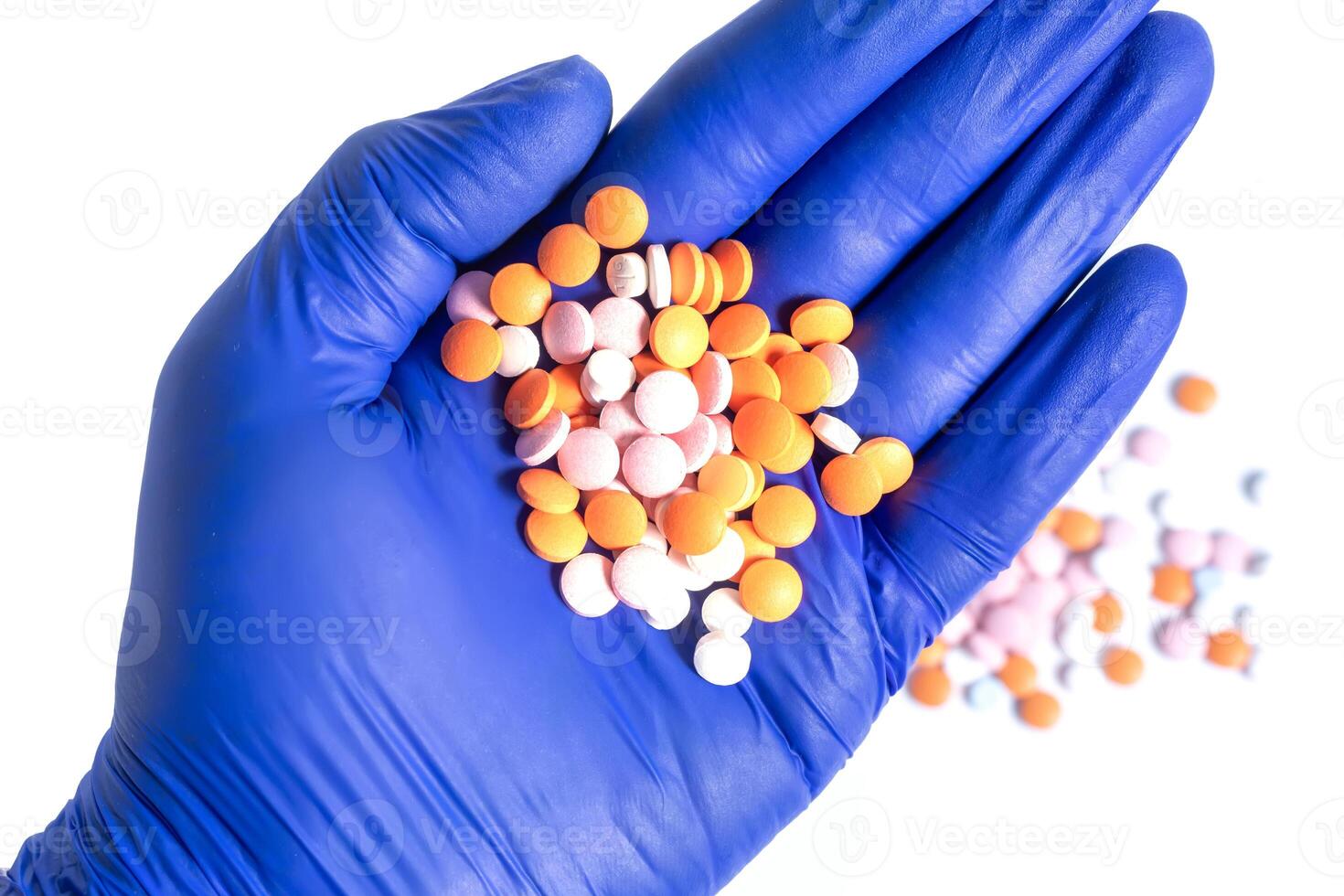 Hand in blue glove holding a pile of multicolor pills isolated on white background. closeup photo