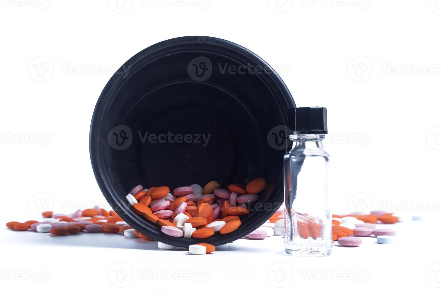 Multicolor pills spilling out of spilled from black plastic box on white background. closeup photo