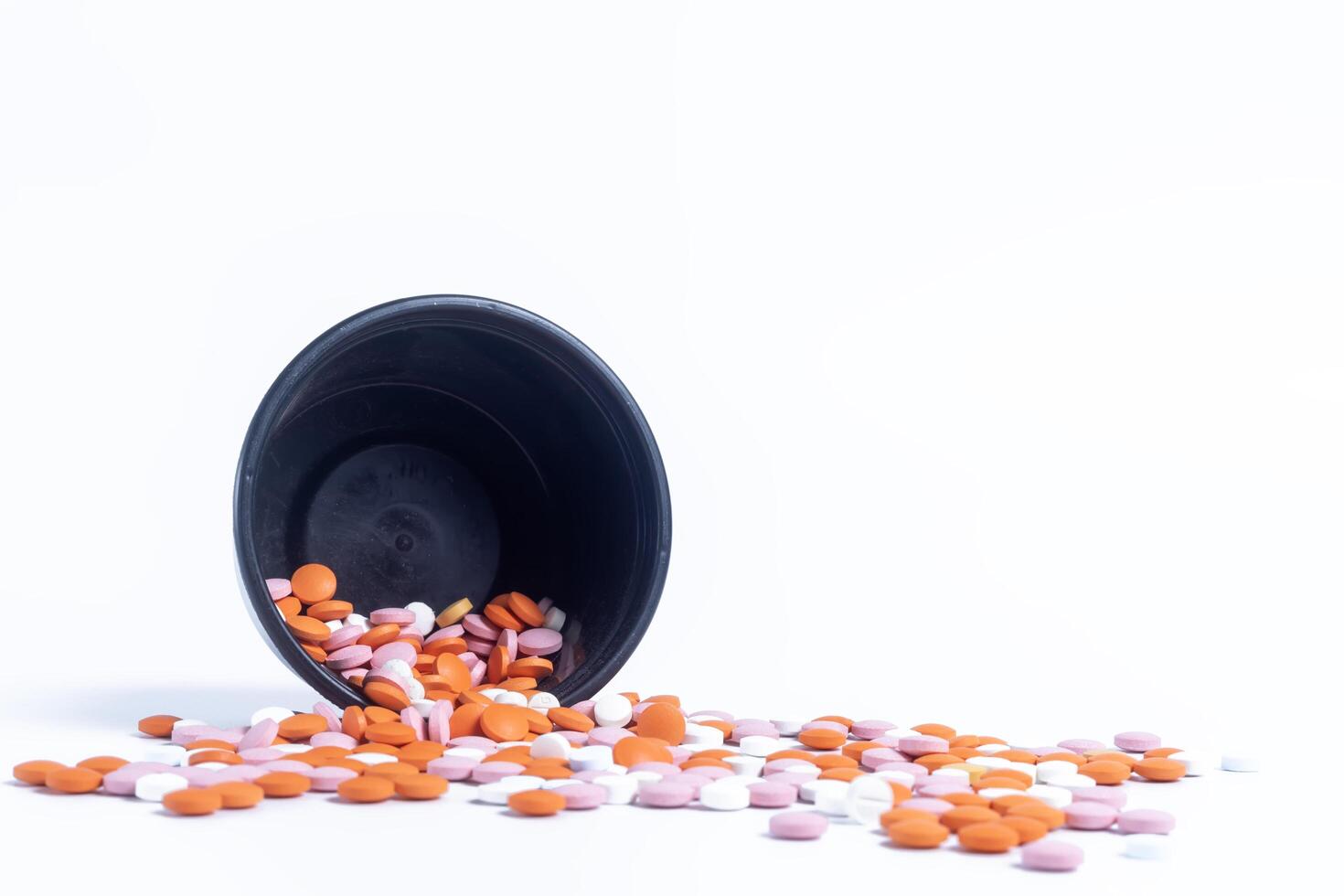 Multicolor pills spilling out of spilled from black plastic box on white background. closeup photo