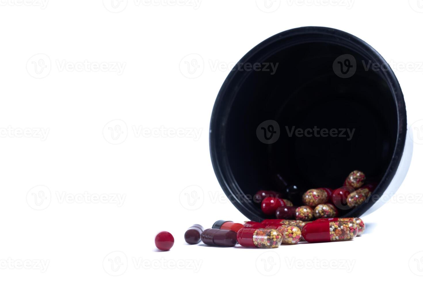 Pills spilling out of a black plastic container isolated on white background photo
