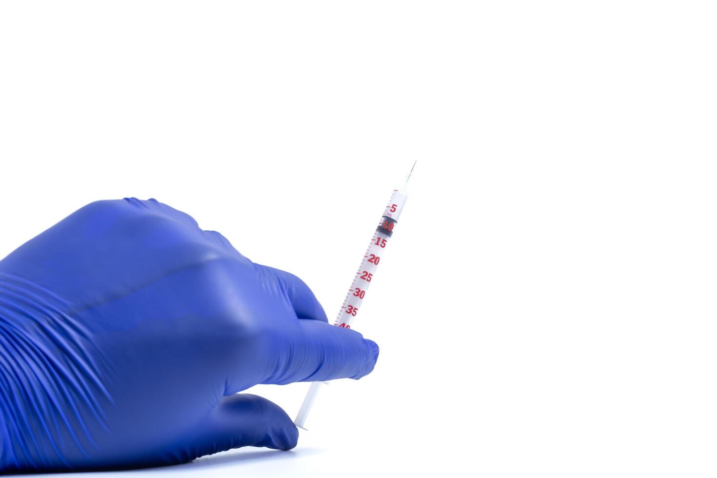 Hand of doctor or nurse in blue gloves holding vaccine syringe on white background. photo