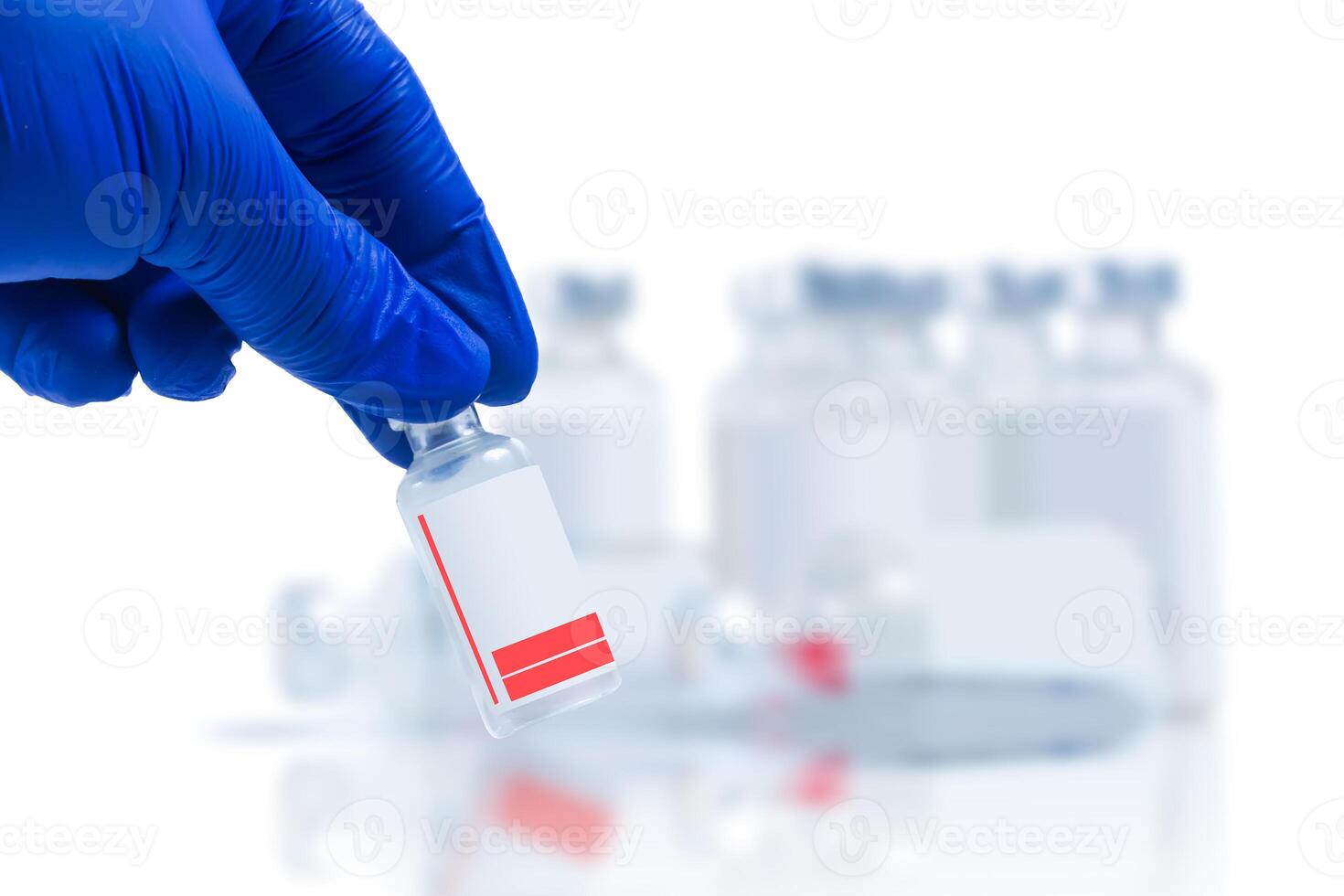 Hand in blue glove holding vial with vaccine sample in front of blurred vaccine vials on white background. Closeup photo