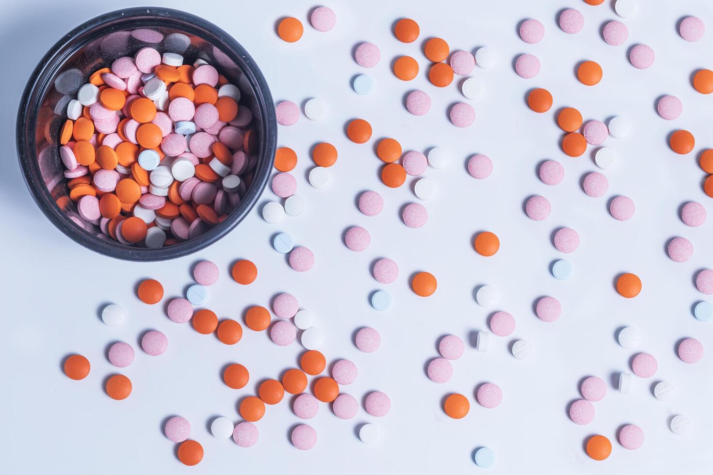 Colorful pills in a round plastic container on white background. photo