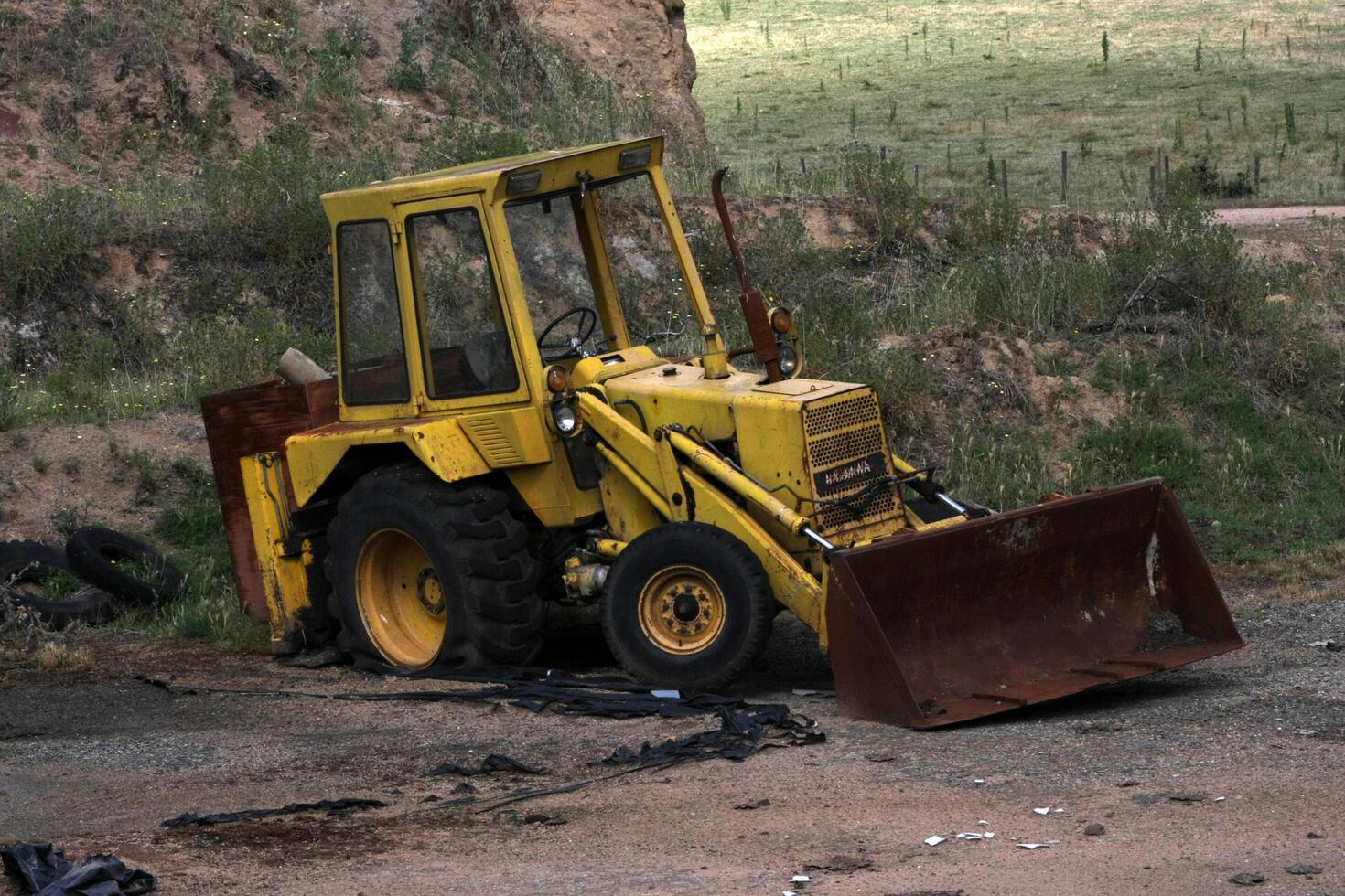 Abandoned backhoe excavator rusting in a forgotten construction site, showcasing years of neglect and decay. photo