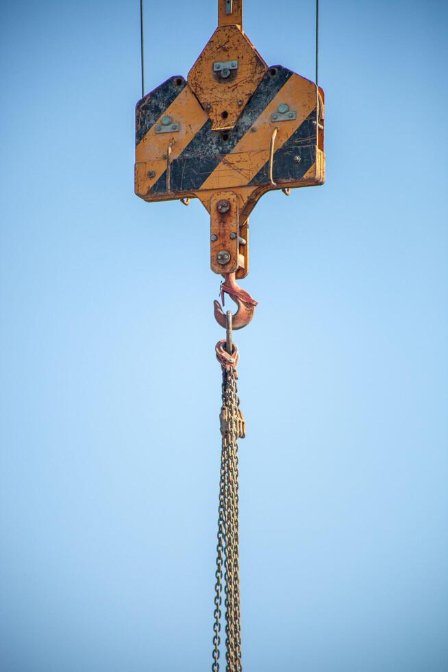 A close-up shot of a crane hook lifting heavy chains, showcasing industrial strength and precision. Perfect for construction, engineering, and heavy machinery themes. photo