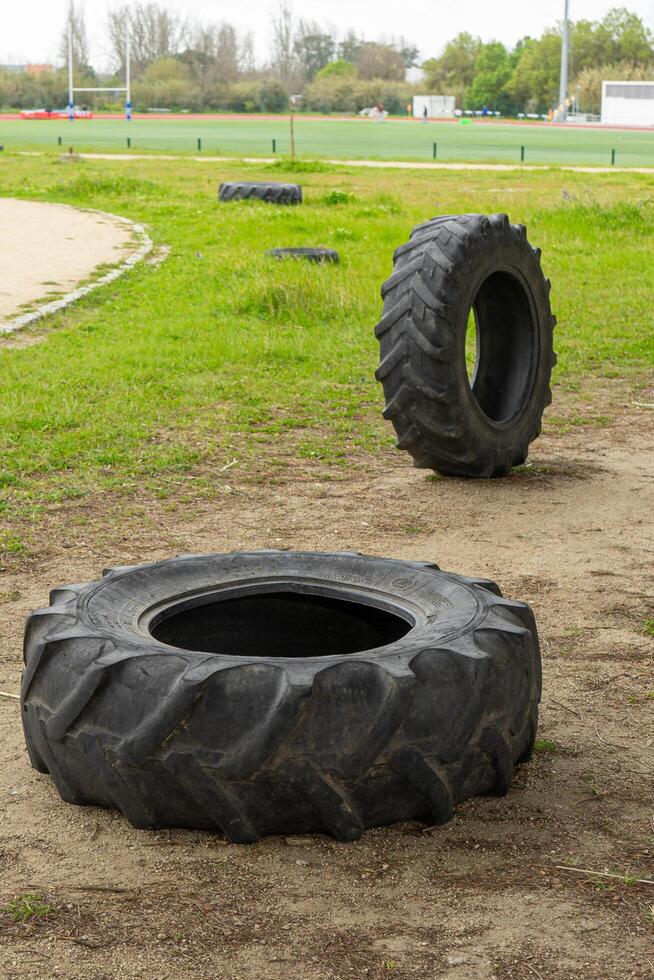 Large tractor tires set up in a sports complex for obstacle courses or CrossFit training. The rugged terrain and equipment add to the challenge and excitement of the workout. photo