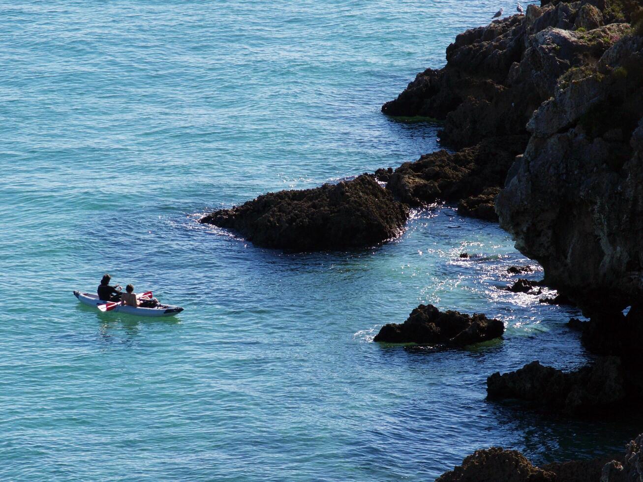 Two people kayaking along the cliffs in Arrabida Natural Park, Setubal, Portugal, showcasing the stunning coastal scenery and adventurous spirit of this beautiful natural reserve. photo