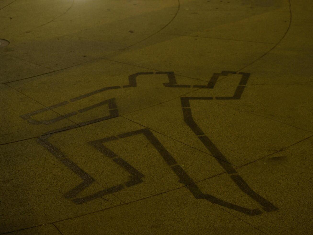 A lifeless body lies on the ground, carefully drawn in chalk. The scene is solemn, capturing the gravity of crime and investigation. Ideal for crime scene, mystery, and detective-themed visuals. photo