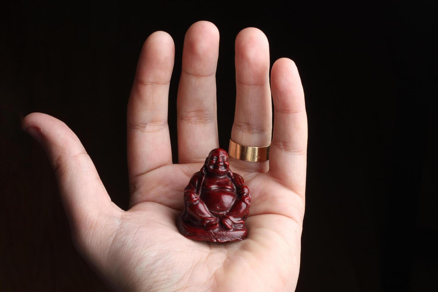 A serene small Buddha statue rests in a man's palm, symbolizing peace and mindfulness. Ideal for concepts of spirituality, meditation, and inner tranquility. photo