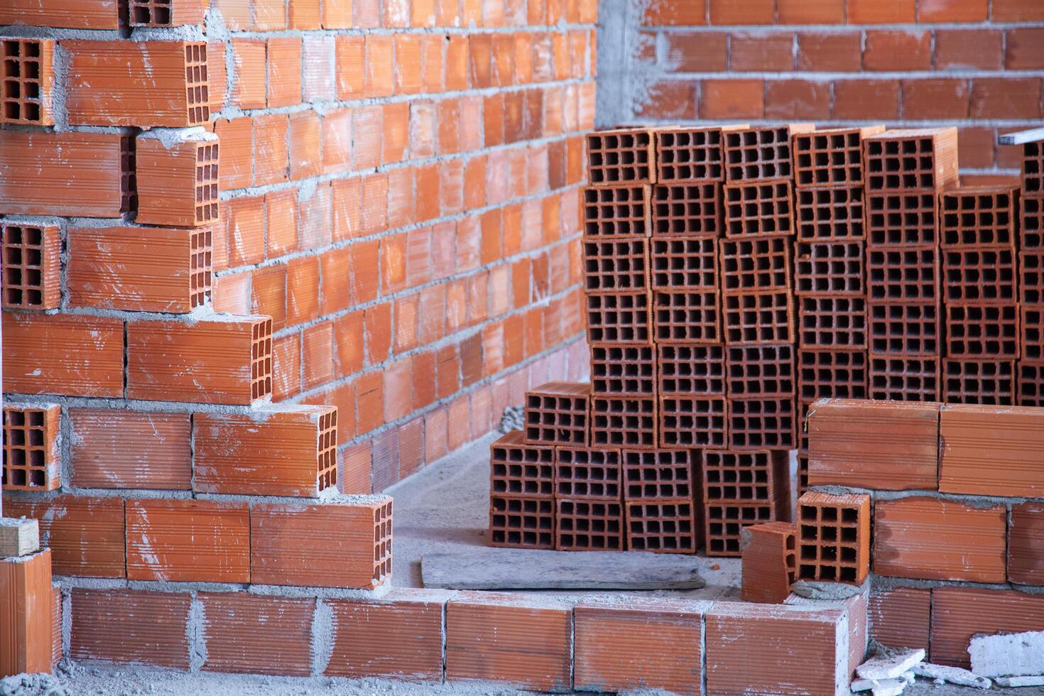 A newly built brick wall stands sturdy, with a stack of unused bricks in the background, ready for future construction. photo