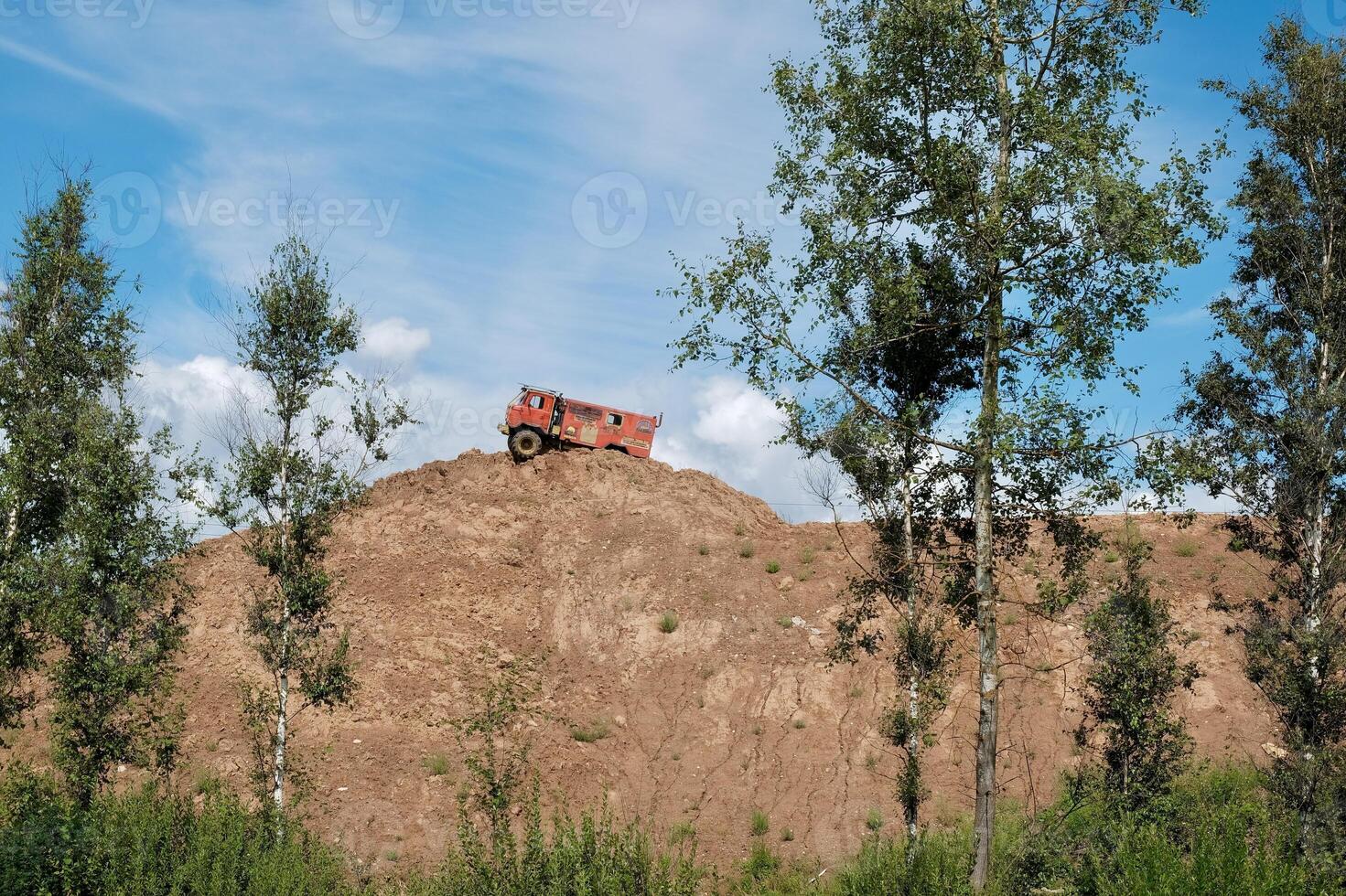 Rally, orange truck on top of a mountain against a blue sky photo