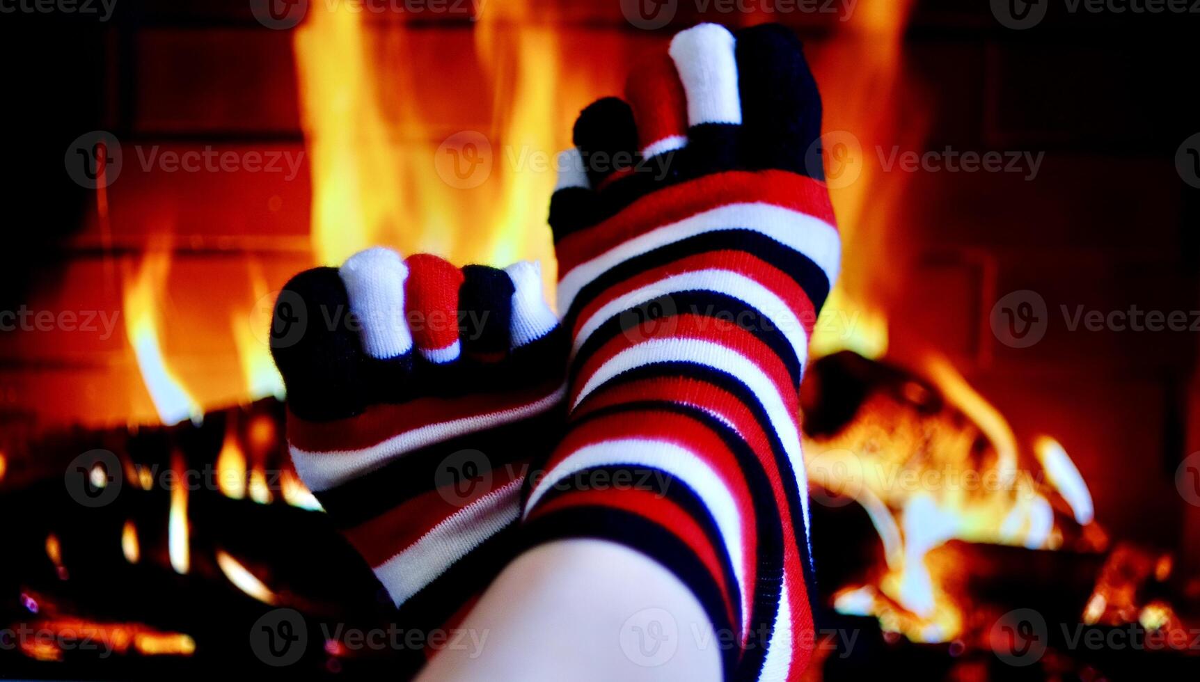 Colorful socks are worn on the legs that are turned to the fireplace to keep warm photo