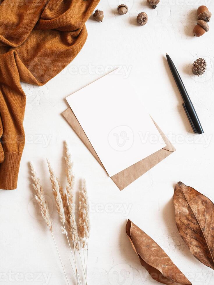Frame from brown sweater, dry grass, fall leaf and acorns, envelope and postcard photo
