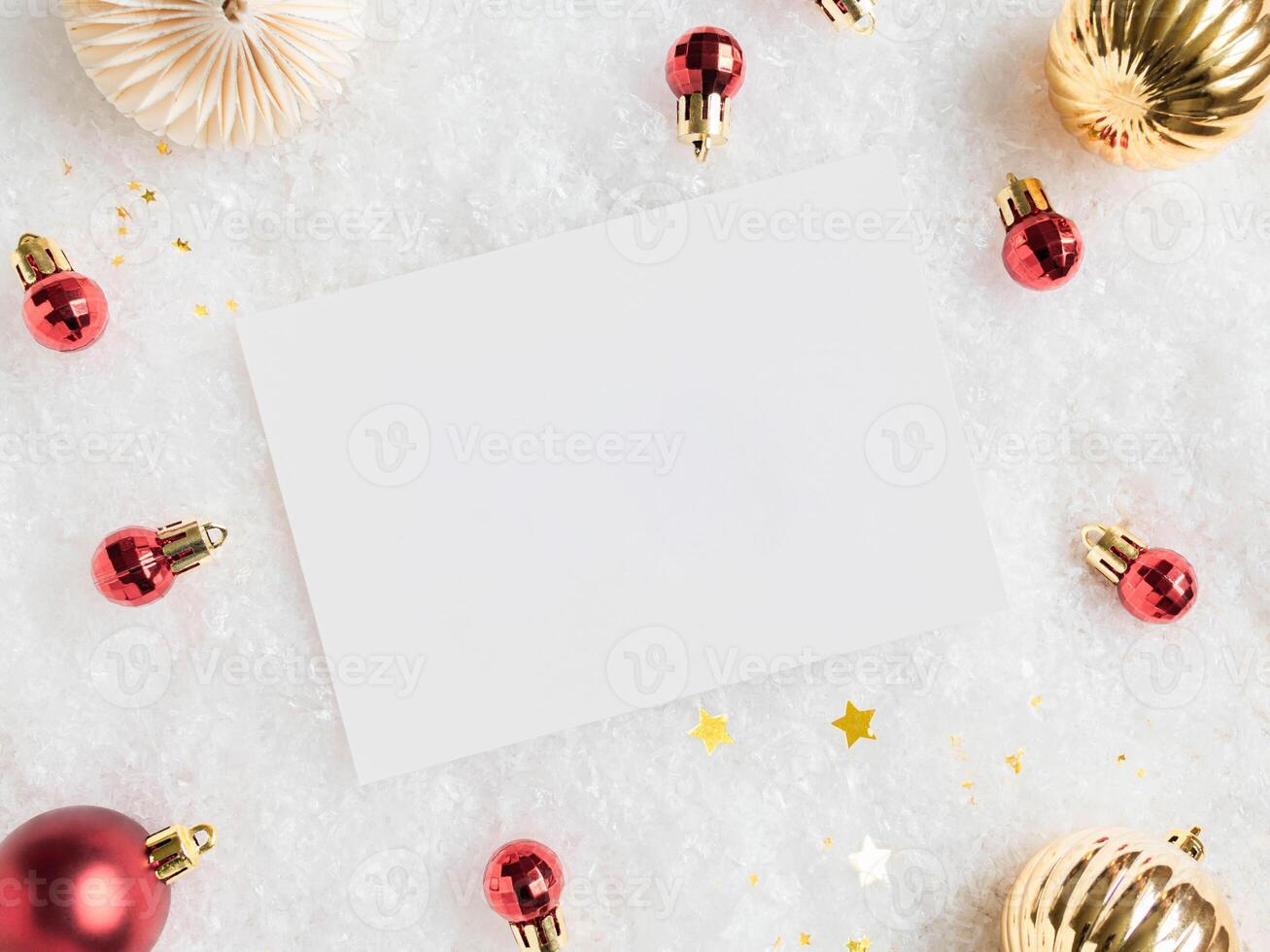 Empty white postcard and various red and gold christmas decor on artificial snow background. photo