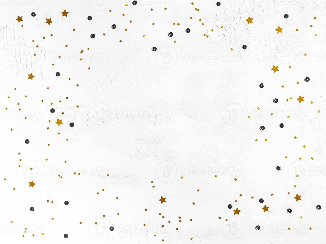 Golden confetti and black sequins frame on white background. photo