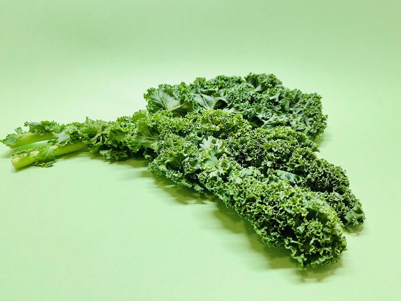 Kale leaf salad vegetable isolated on green background. Creative layout made of kale closeup. Food concept. photo