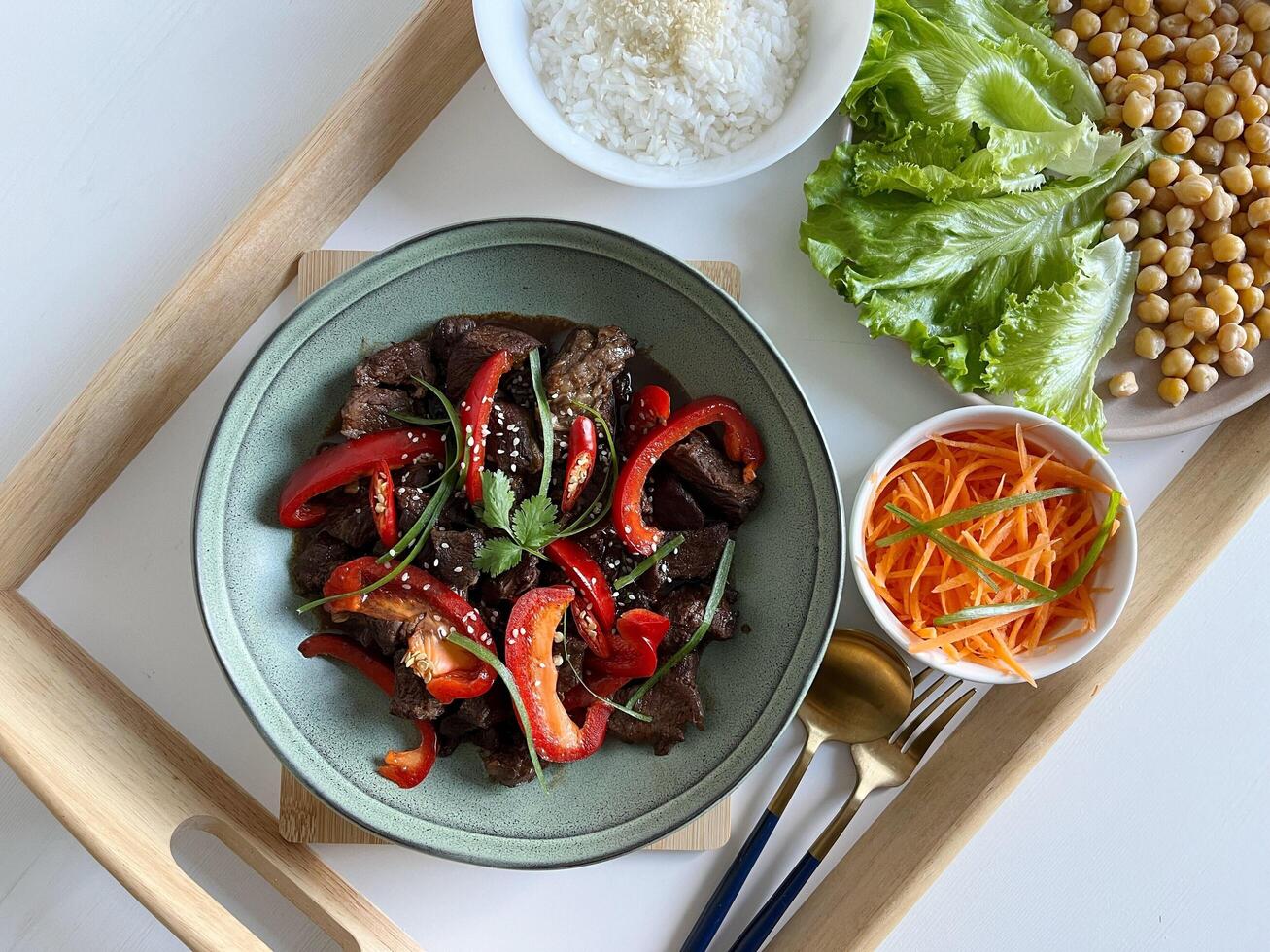 Asian food Beef Teriyaki with red paprika and sesame seed on a plate. Assortment of vegetables and rice on the table. Top View photo