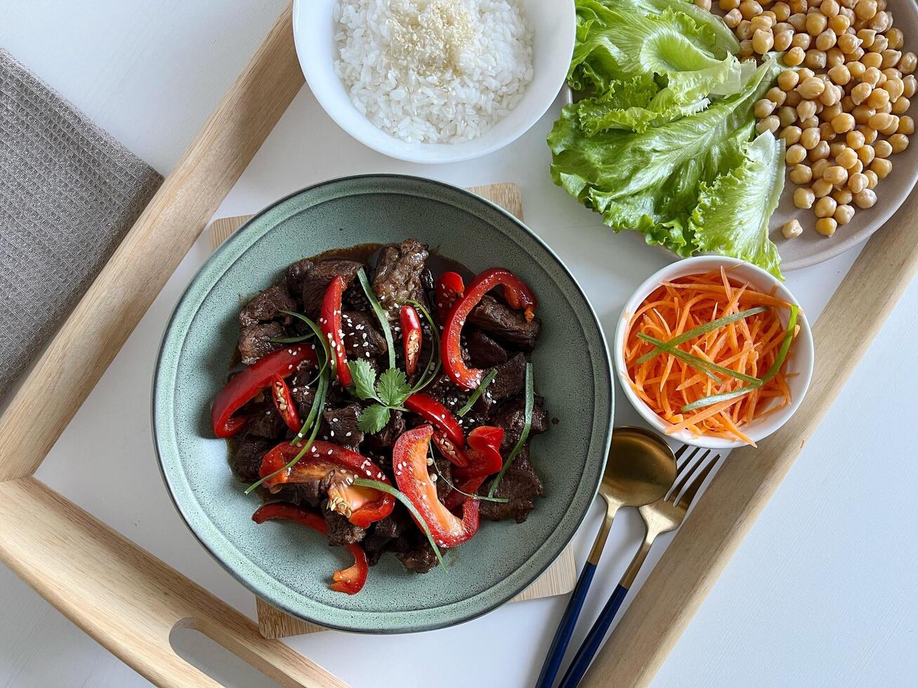 Asian food Beef Teriyaki with red paprika and sesame seed on a plate. Assortment of vegetables and rice on the table. Top View photo