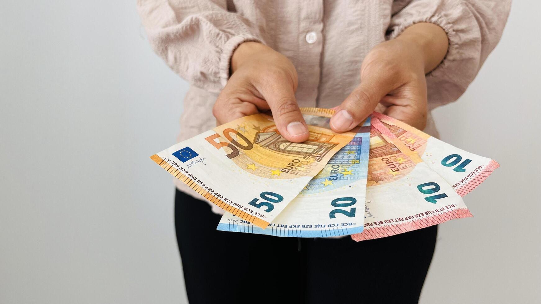 Woman holding euro money. Giving bunch of money with different bills, euro banknotes, European Union paper currency. Finance, business, investment, inflation, purchasing power and social crisis. photo