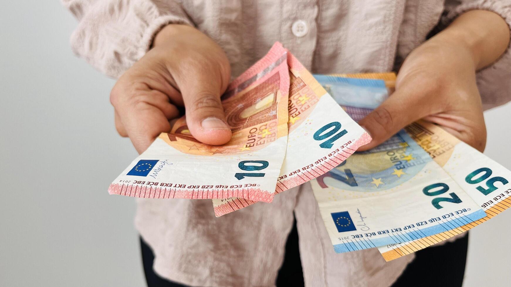 Woman holding euro money. Giving two 10 euro notes and holding different bills, euro banknotes, European Union paper currency. Finance, business, investment, inflation, purchasing power photo