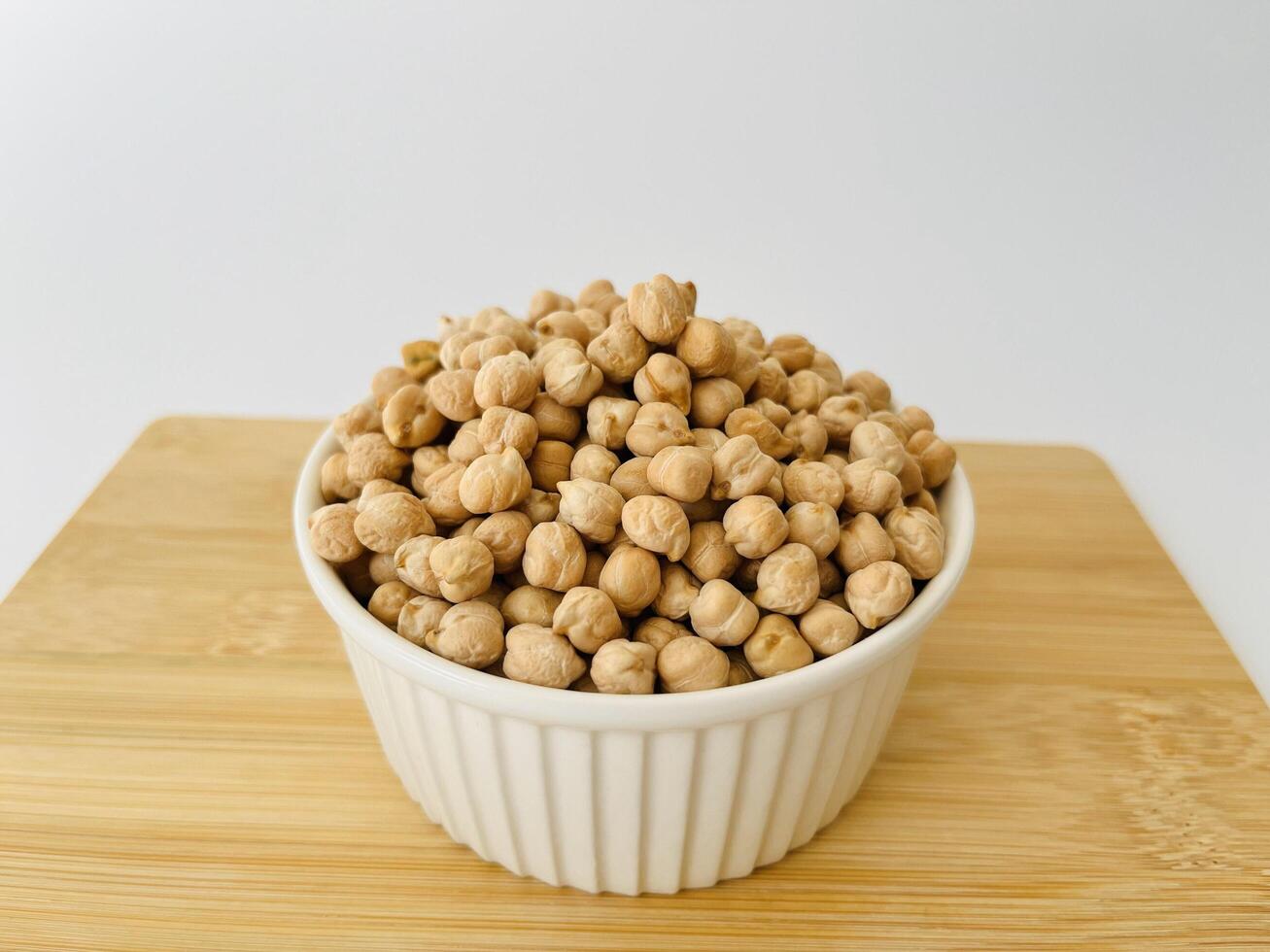Raw dry chickpea in small ceramic bowl on white background. Traditional ingredient for cooking hummus. Middle Eastern and Mediterranean cuisine. Selected focused photo