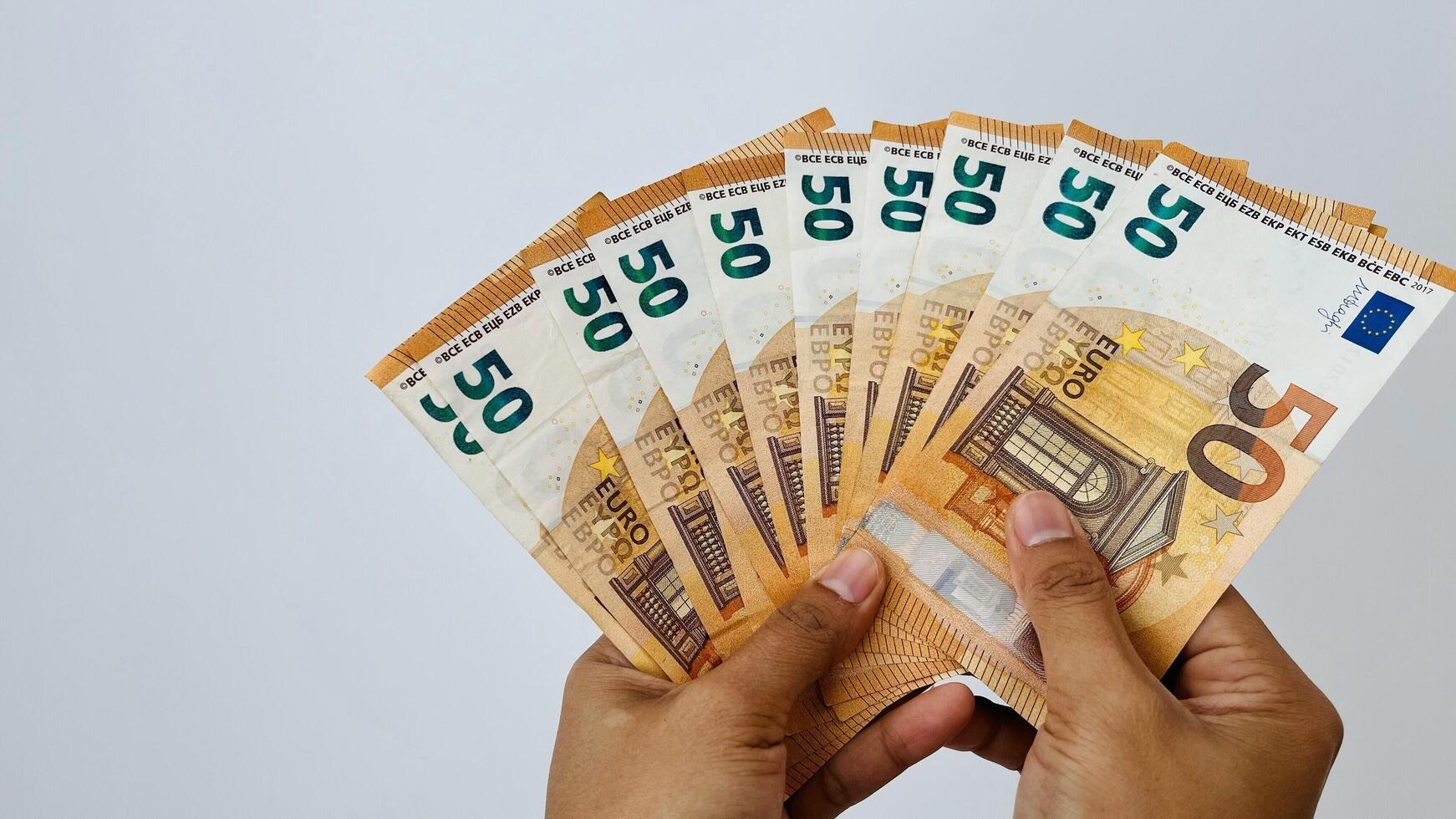 A closeup shot of hand holding 50 euro notes. Euro banknotes, European Union paper currency. Saving money concept. Finance, business, investment, inflation, purchasing power photo