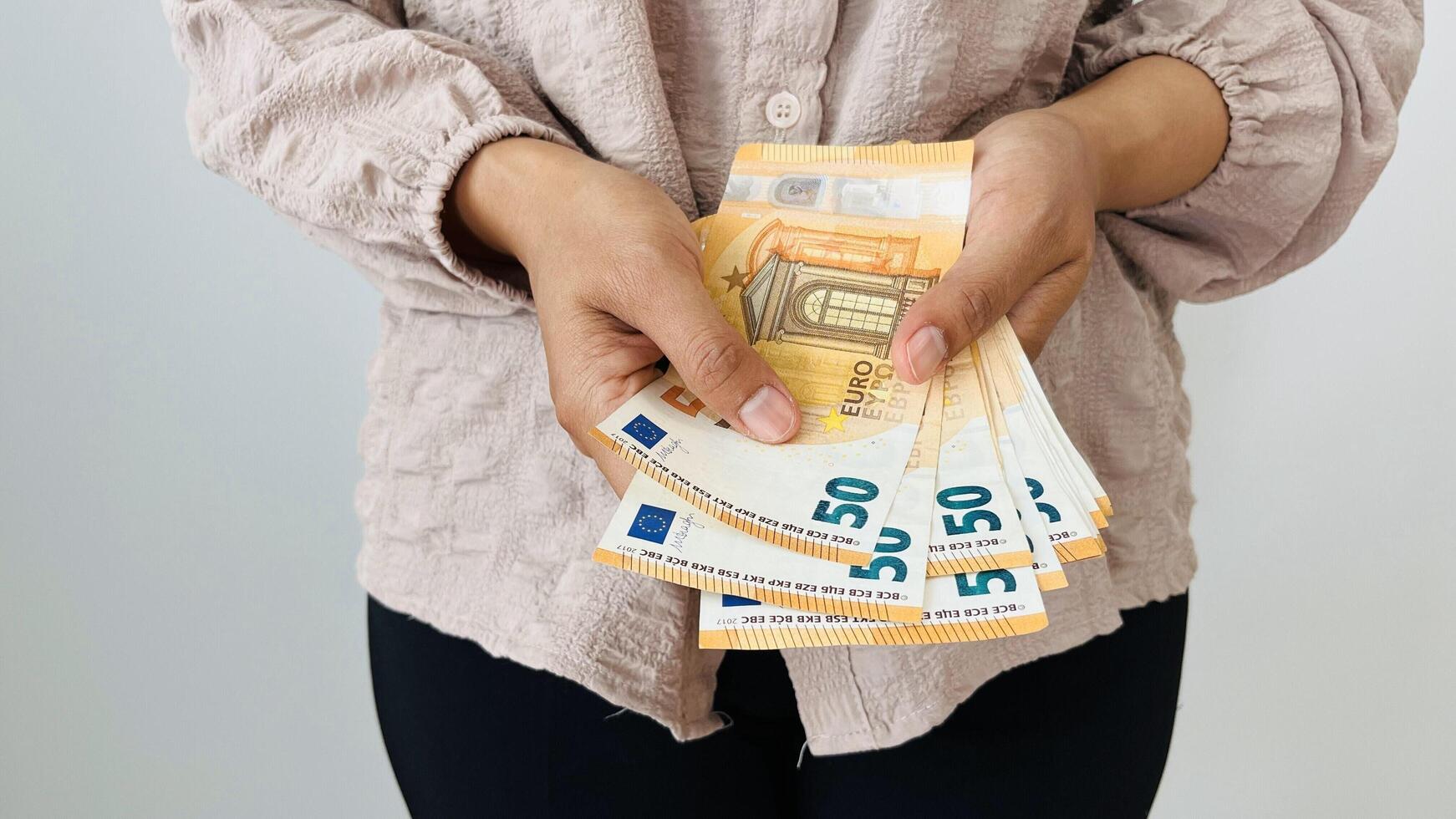 Woman holding bunch of 50 euro money. Euro banknotes, European Union paper currency. Saving money concept. Finance, business, investment, inflation, purchasing power and social crisis. Keeping savings photo