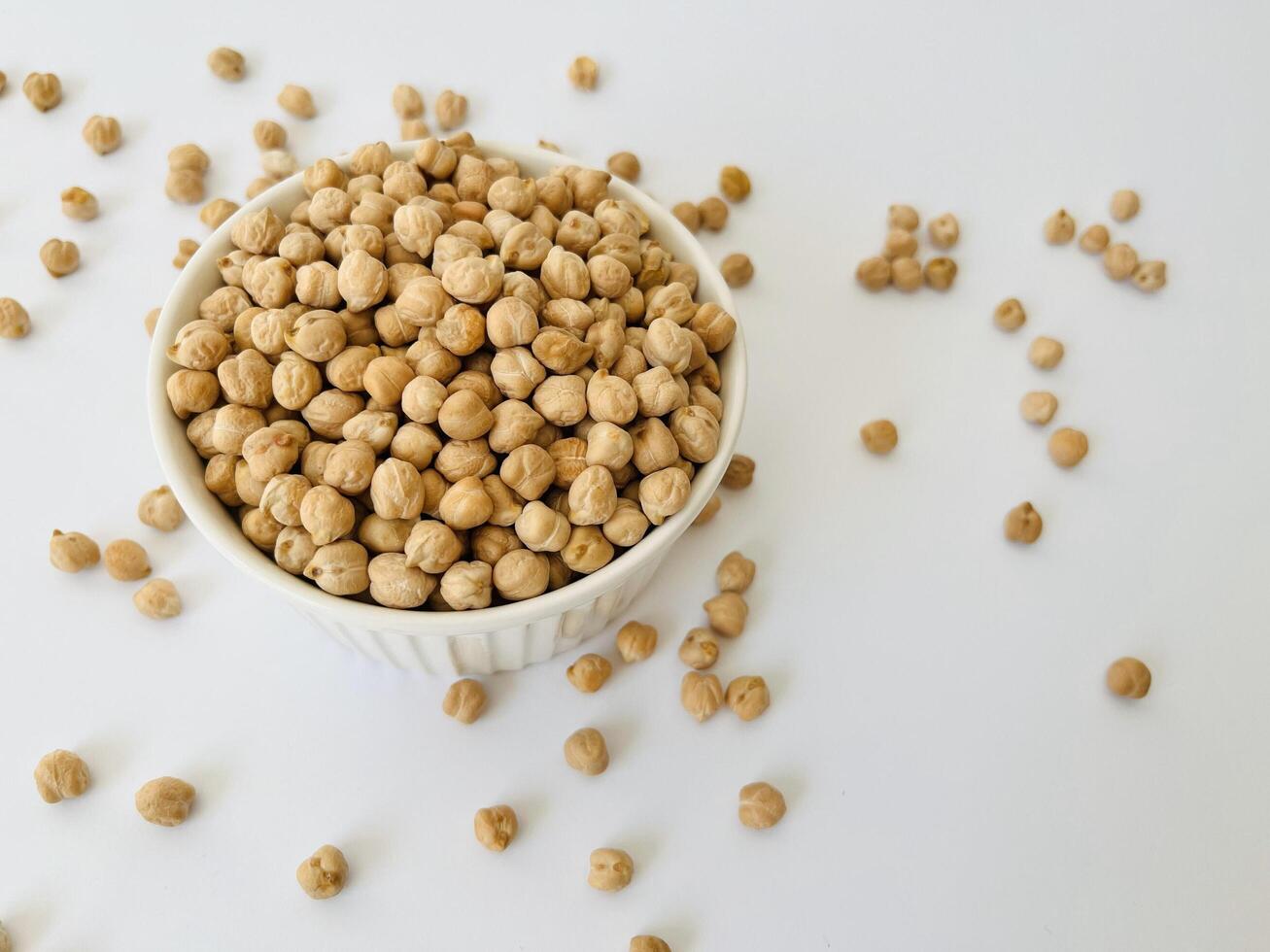 Raw dry chickpea in small ceramic bowl on white background. Traditional ingredient for cooking hummus. Middle Eastern and Mediterranean cuisine. Selected focused photo