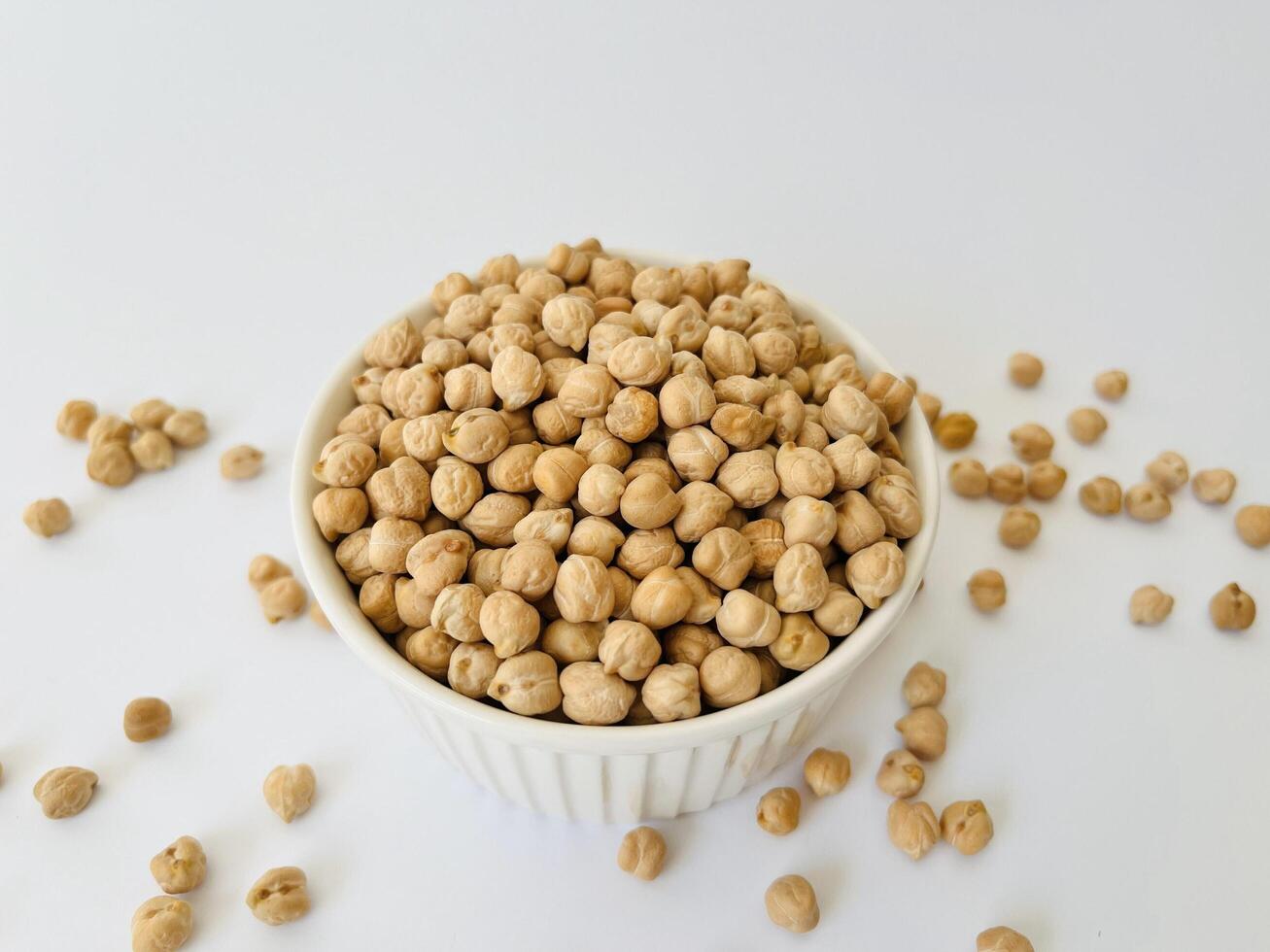 Raw dry chickpea in small ceramic bowl on white background. Traditional ingredient for cooking hummus. Middle Eastern and Mediterranean cuisine. Selected focused photo