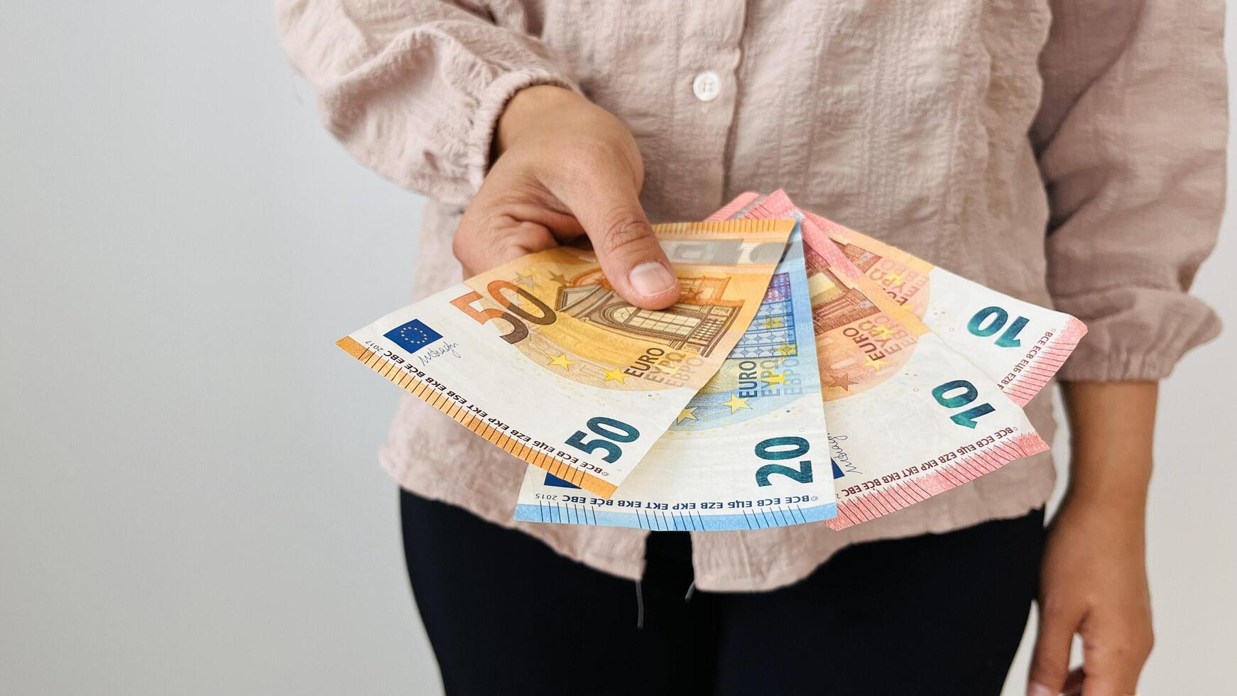 Woman holding euro money. Giving bunch of money with different bills, euro banknotes, European Union paper currency. Finance, business, investment, inflation, purchasing power and social crisis. photo