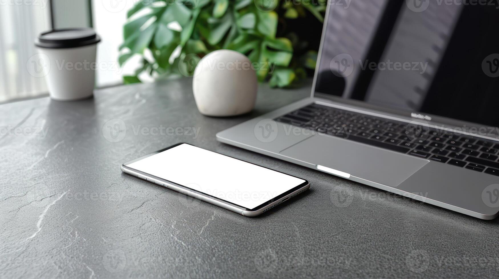 phone and laptop on table with plants in background, photo