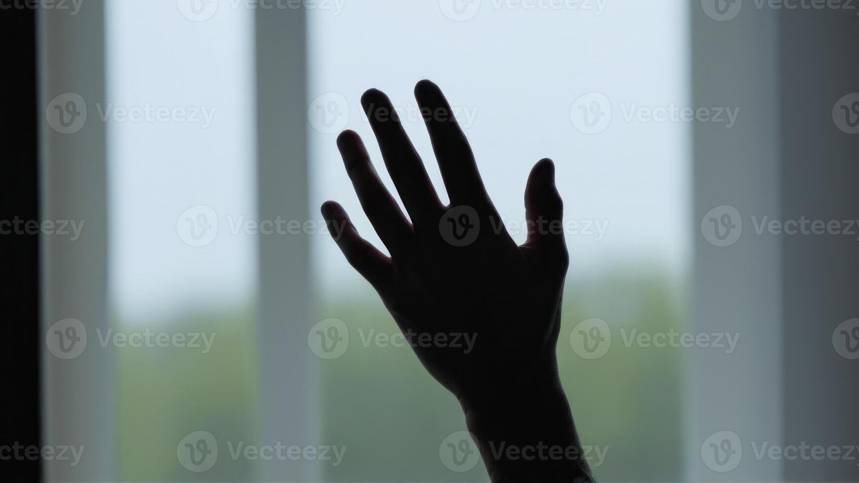 a person with an open hand silhouetted against a window, photo