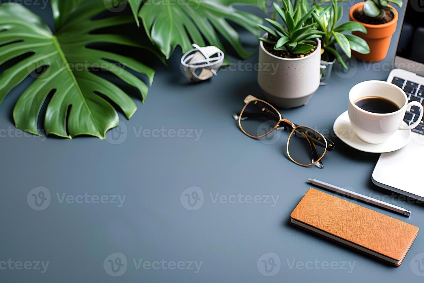 a desk with a cup of coffee and an apple laptop computer, next to some plants, photo