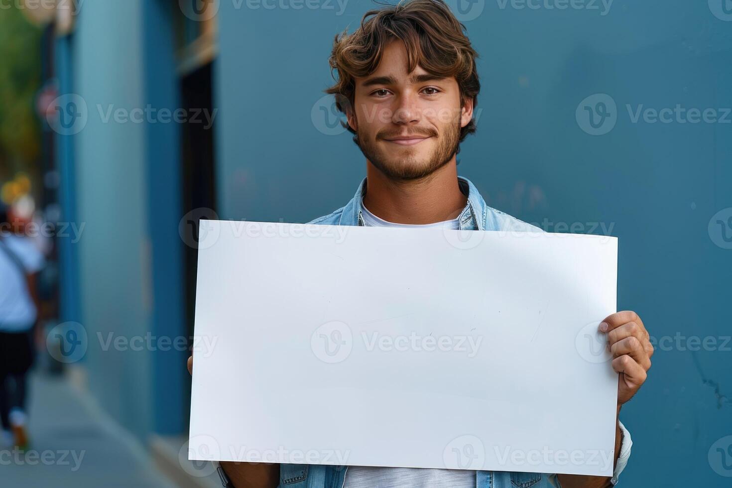 a man holding up a blank sign on the side of the road, photo