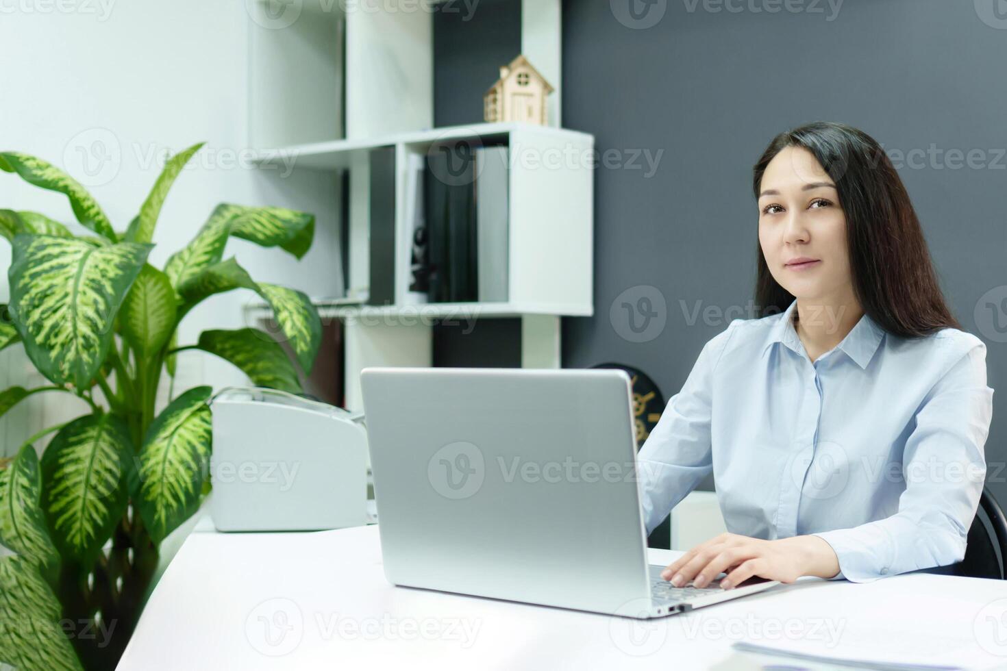 A young girl in a modern office working diligently at her desk, concentrating on things on her computer photo