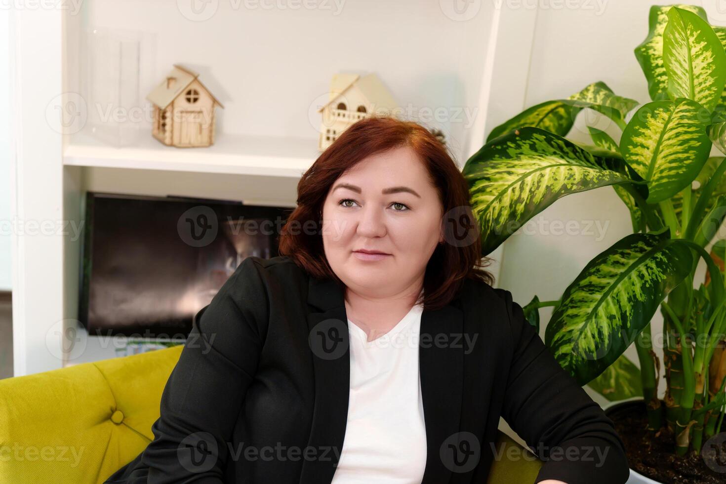 portrait of an older woman sitting on a couch in a modern office with a smile and confidence photo