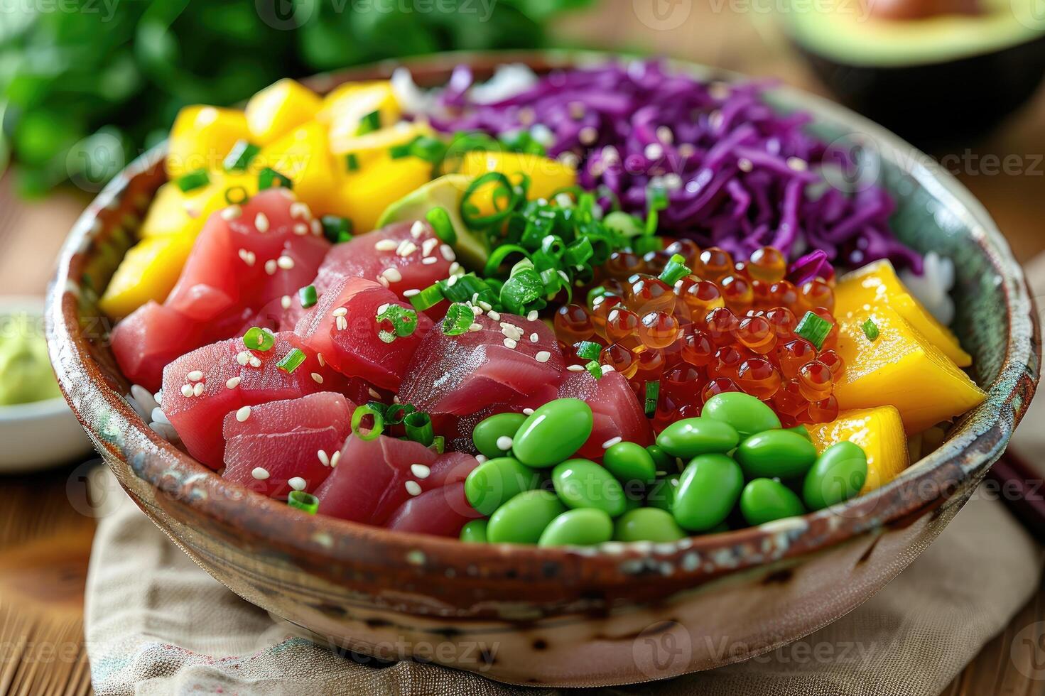 A colorful poke bowl featuring fresh tuna, diced mango, edamame, roe, purple cabbage, and avocado in a ceramic bowl, topped with sesame seeds and green onions. photo