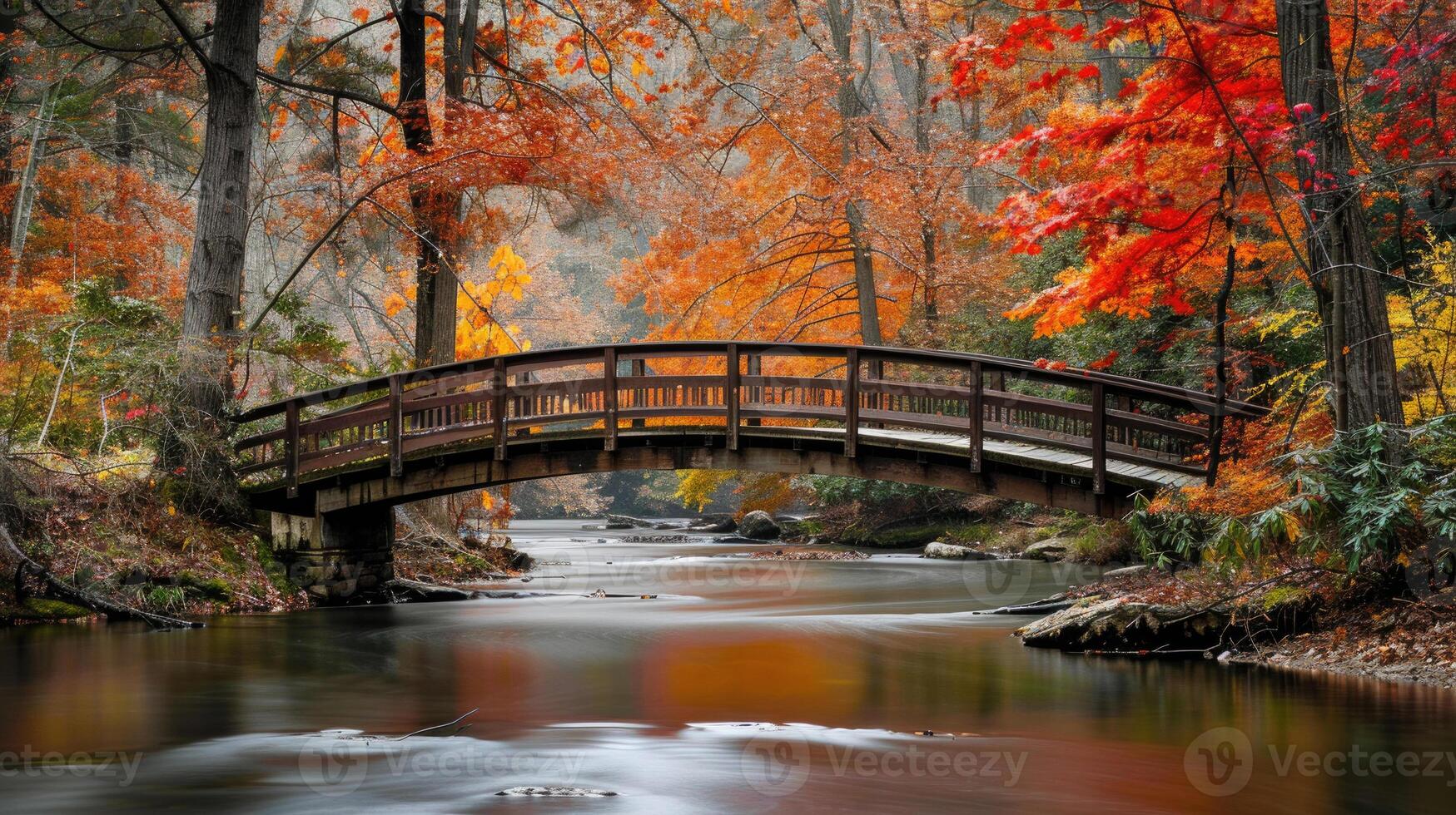 A bridge over a stream surrounded by colorful autumn leaves. photo