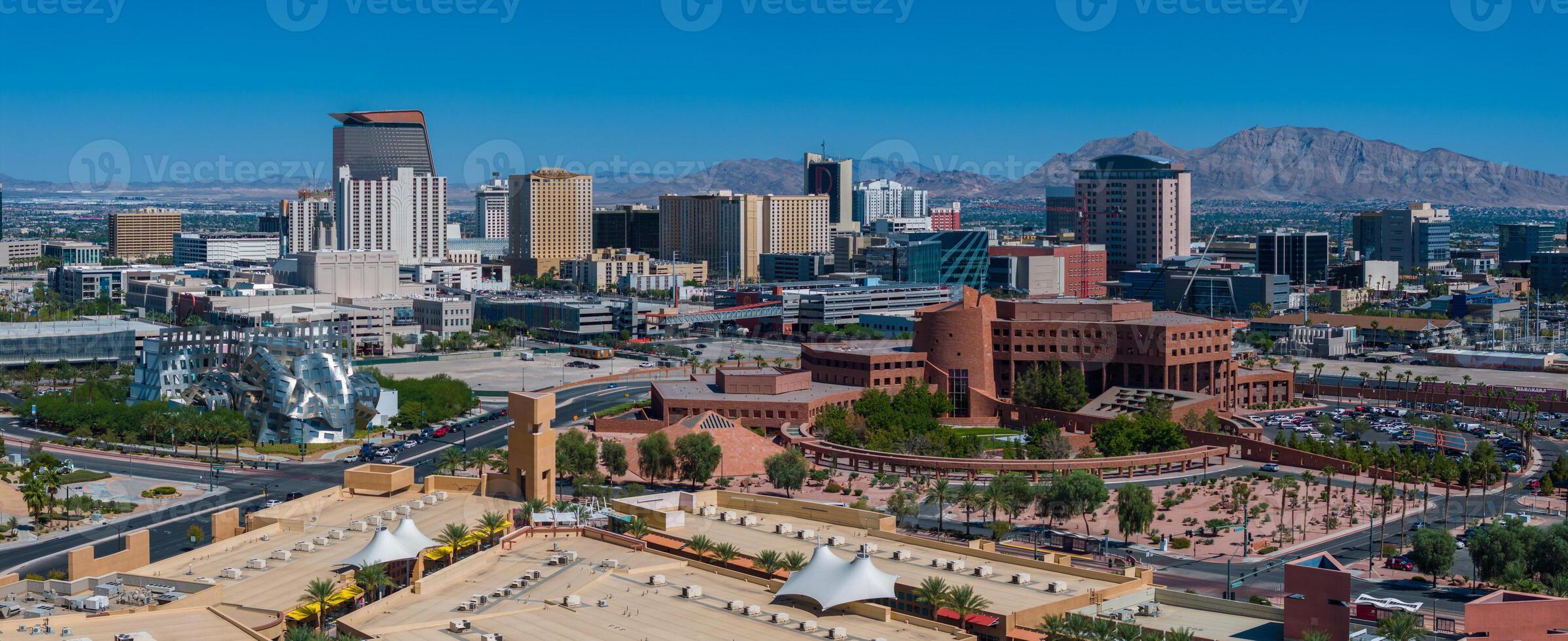 Aerial View of Bustling Cityscape with Modern High-Rises and Green Parks Against Mountainous views photo