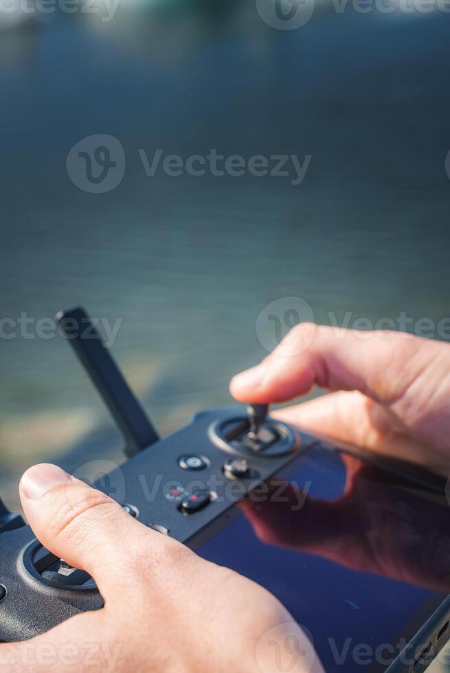 Close-Up of Hands Operating Drone Controller with Water in Background photo
