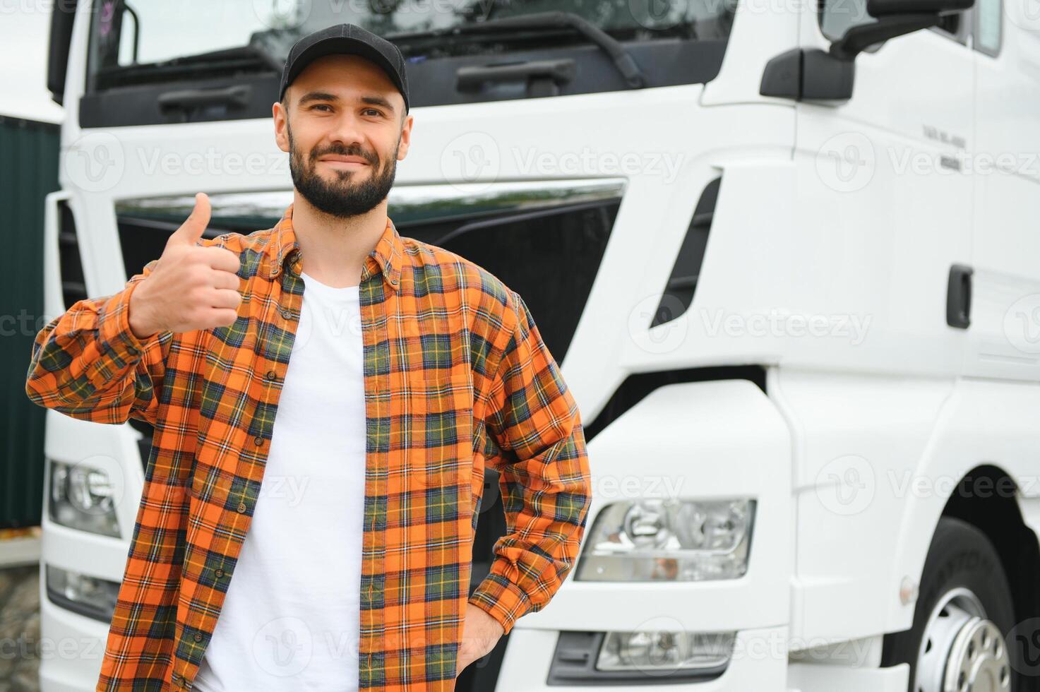 Portrait of young bearded trucker standing by his truck vehicle. Transportation service. Truck driver job photo
