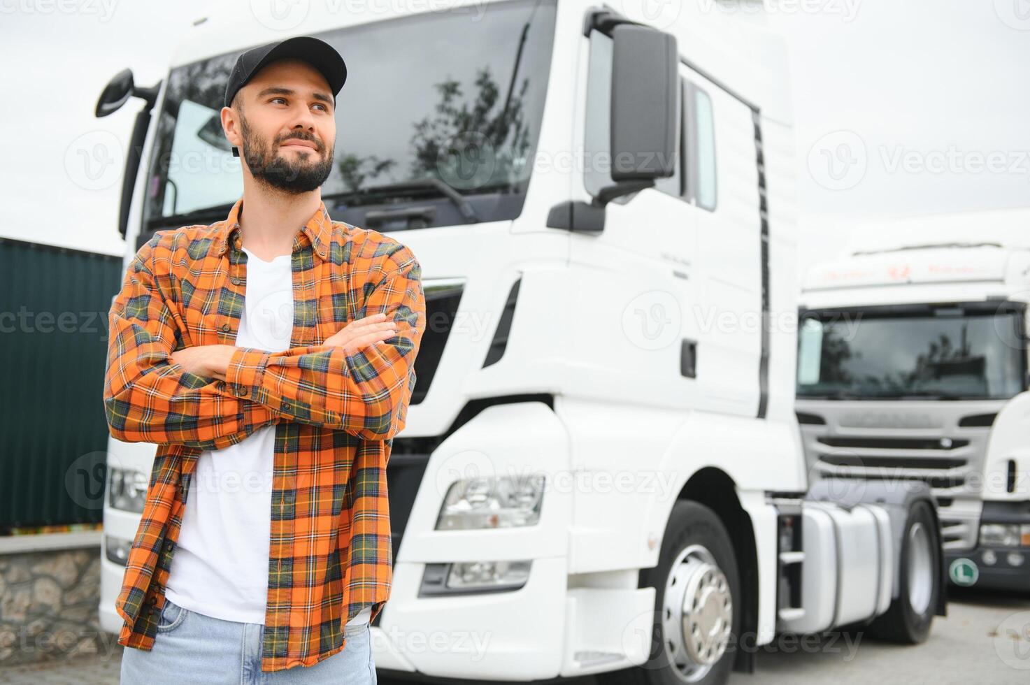 Portrait of young bearded man standing by his truck. Professional truck driver standing by semi truck vehicle. photo