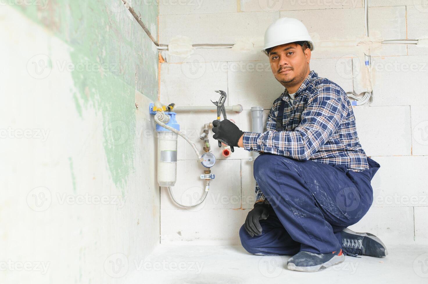 Indian plumber installing water equipment - meter, filter and pressure reducer photo