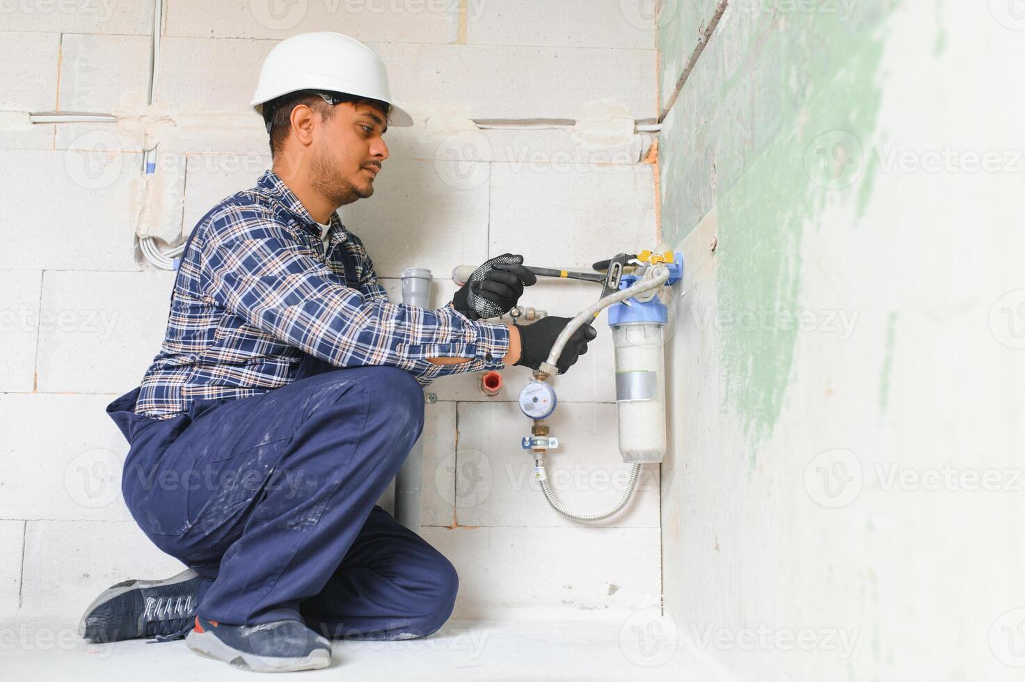 Indian plumber installing water equipment - meter, filter and pressure reducer photo