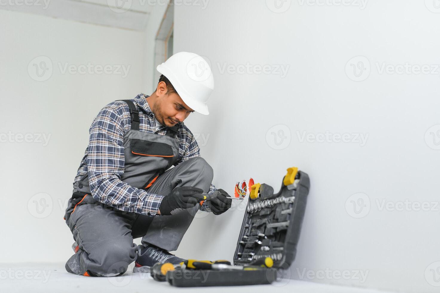 an Indian electrician installs an outlet in a new building photo