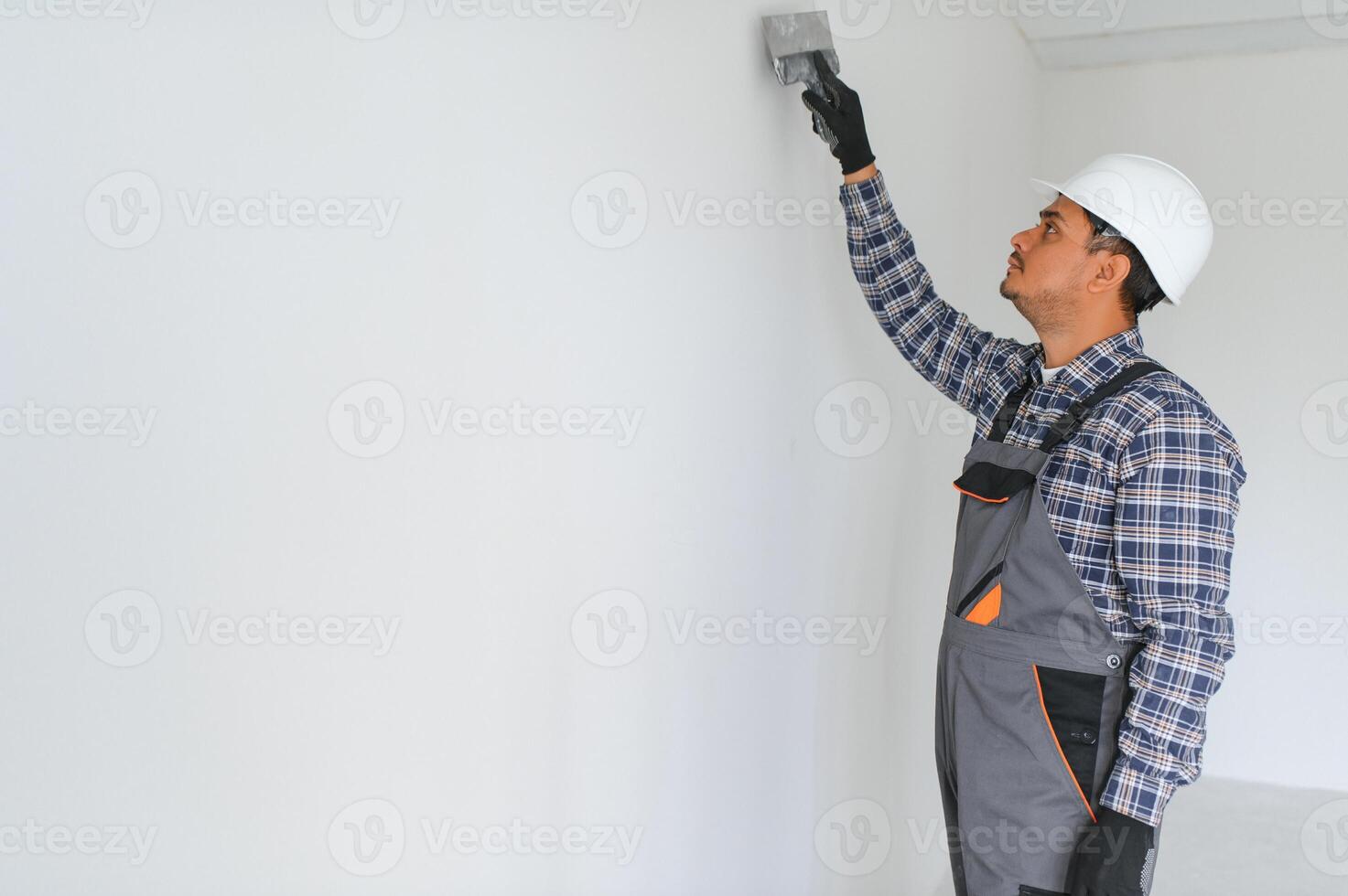 An Indian worker works in an empty apartment. A man in a uniform makes repairs inside the building photo