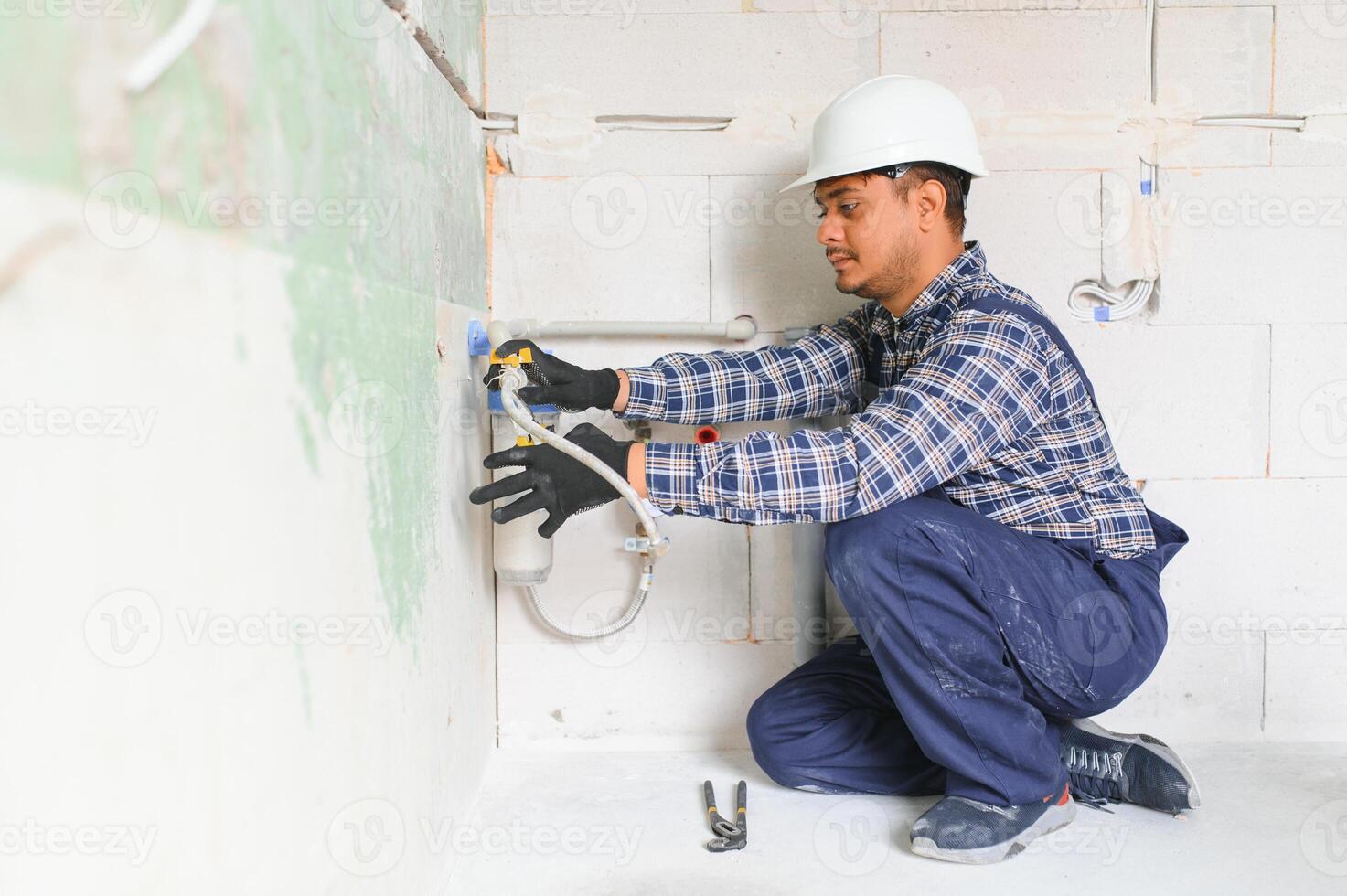 Indian plumber installing water equipment - meter, filter and pressure reducer photo
