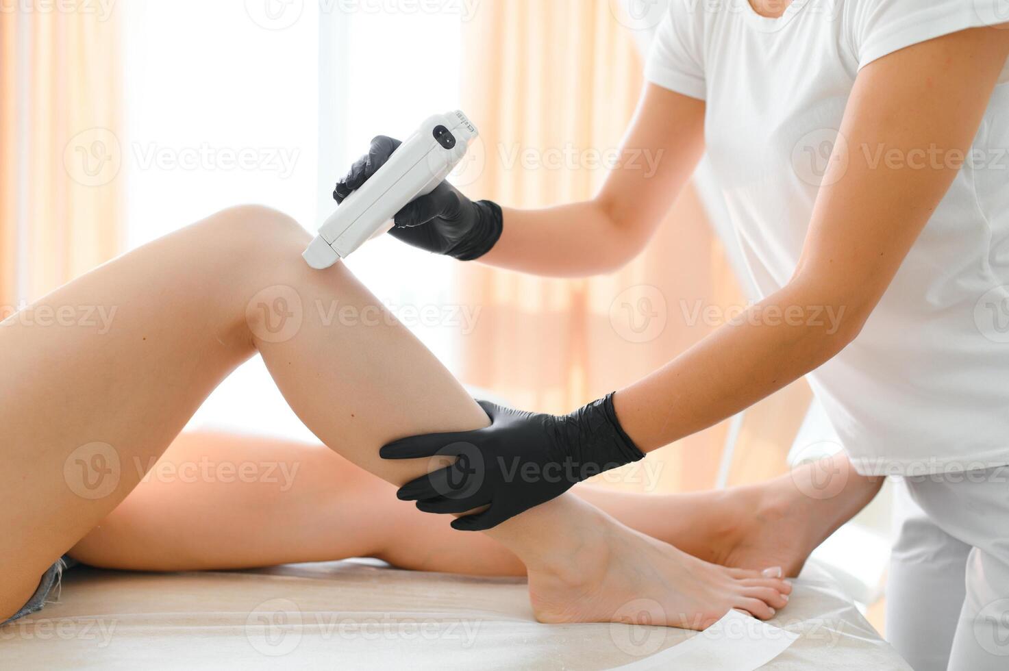 Beautician waxing female legs in spa center photo