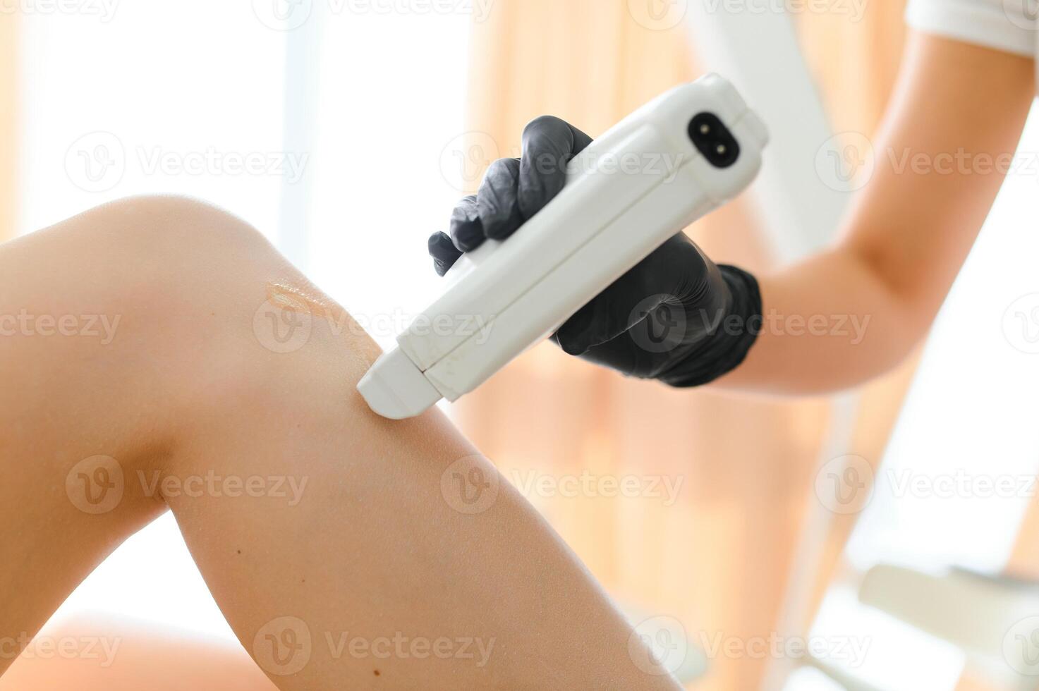 Beautician waxing female legs in spa center photo